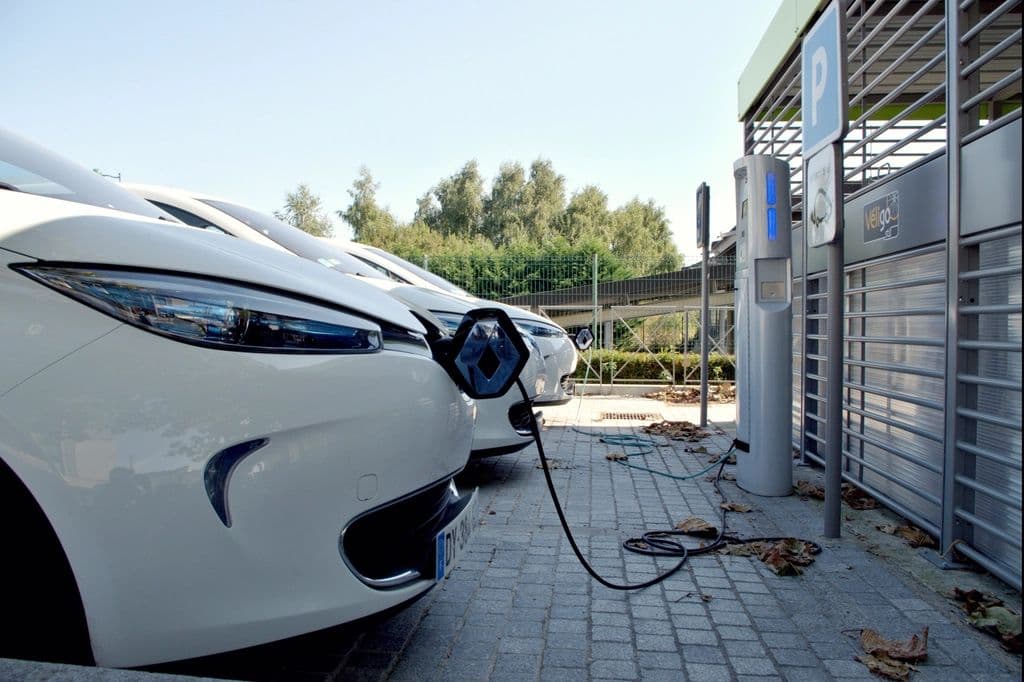Electric cars plugged in at a row of charging stations